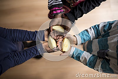 Three kids of mixed races each holding a piece of apple in the p Stock Photo