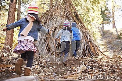 Three kids play outside shelter made of branches in a forest Stock Photo