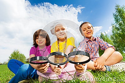 Three kids sitting close together with magnifiers Stock Photo