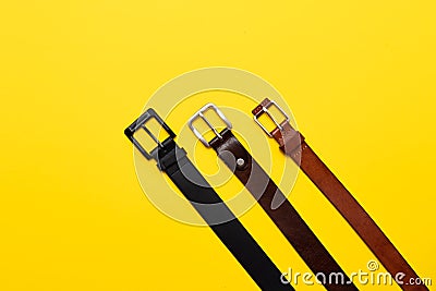 Three leather belt for trousers on yellow background. Top view flat lay Stock Photo