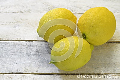Three lemons on a white wooden table. Stock Photo
