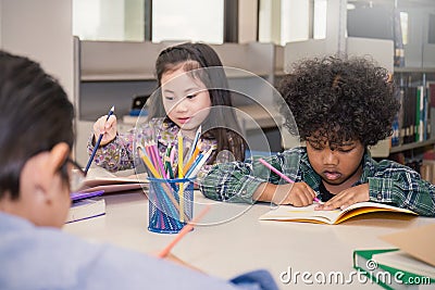 Three little children sitting hand holding pencil and coloring picture Stock Photo