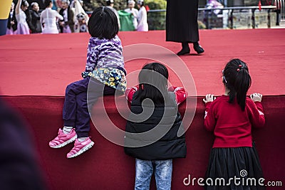 Three little girls leaning on the edge of the stage, absorbed in the performance Editorial Stock Photo