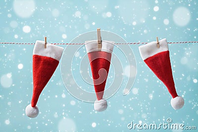 Three little Santa Claus hat hanging on a string against blue snowy background. Christmas and New year concept. Greeting card Stock Photo
