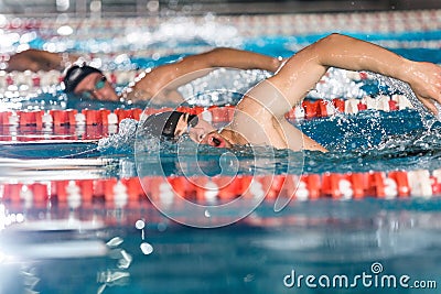 Three male swimmers doing free style in different swimming lanes Stock Photo