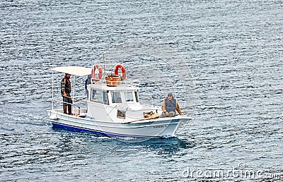 Three male Turkish fisherman on a white traditional fishing boat sailing over the sea in Gumusluk, Bodrum, Turkey Editorial Stock Photo