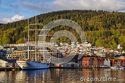 Bergen harbor with schooner, picturesque town and forested hill, Norway Editorial Stock Photo