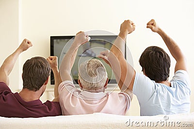 Three Men Watching Widescreen TV At Home Stock Photo