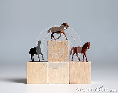 Three miniature racehorses standing on a block of trees shaped like a podium. Stock Photo