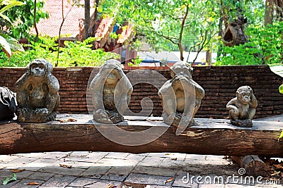 Three monkey statue sit on nature background and hand small statues with the concept of see no evil, hear no evil and speak no Stock Photo