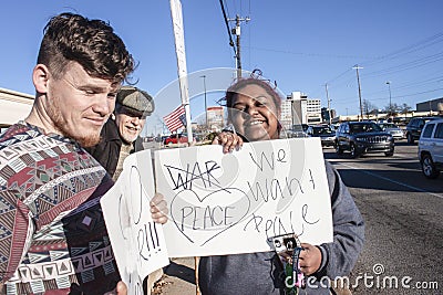 Three multi cultural and generational smiling protesters with anti-war signs stand near intersection Editorial Stock Photo