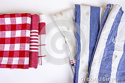 Three new red checkered kitchen picnic towels folded versus old dirty torn blue cloth towels. Cleaning and regularly changing Stock Photo