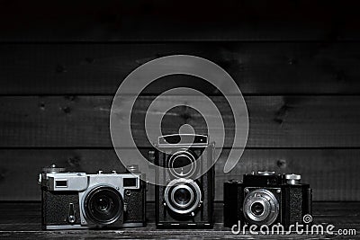Three film cameras on a dark wooden background Stock Photo