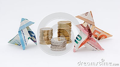 Three origami birds made of 10, 20 and 50 euro banknotes, around stacks of euro coins Stock Photo