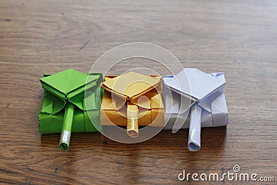 Three origami army tanks on a wooden table top. Stock Photo