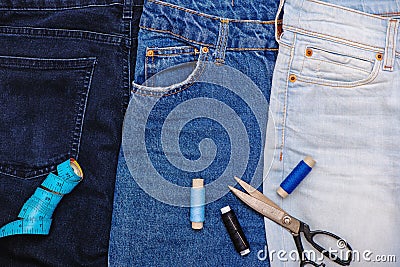 Three pair of jeans with scissors, threads and tailor meter. Stock Photo