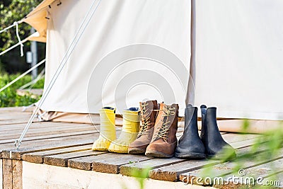 Three pair of shoes on wooden terrace behind a canvas tent Stock Photo