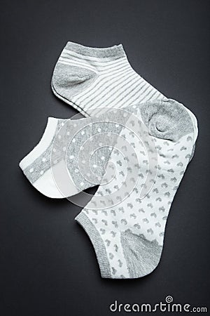 Three pairs of female gray socks: striped, polka dots and hearts on a black background, vertically Stock Photo