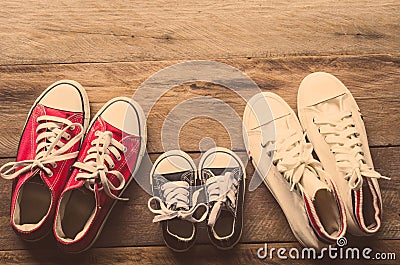 Three pairs of shoes lay on the wooden floor of the family, parents and children to do together Stock Photo