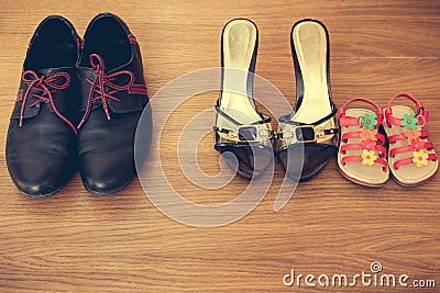 Three pairs of shoes: men, women and children. Baby sandals stand next to womens shoes. Stock Photo