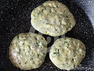 Three pancakes with spinach cooking on frying pan Stock Photo