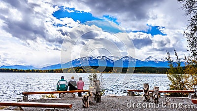 Three People enjoying the view of Pyramid Lake with the Whistlers Mountain in the background in Jasper National Park Stock Photo