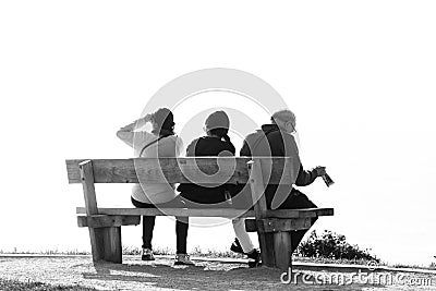 Three people rests on a wooden bench Editorial Stock Photo