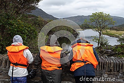 Three people waiting on a bridge wearing life jackets while they wait for a boat at the Meeting of the Waters, Ring of Kerry, Editorial Stock Photo