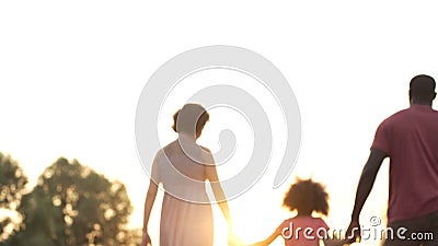 Three person family walking into sunset, happy future together, memories Stock Photo