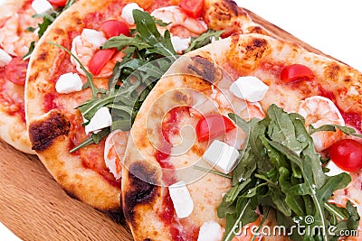Three pizzas with prawns, tomatoes, arugula and cheese on a wooden background Stock Photo