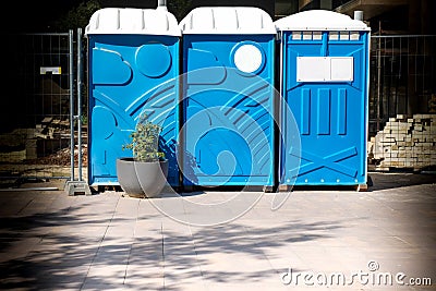 Three portable blue WC toilet cabins at construction site Stock Photo