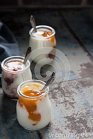 Three portions of fresh natural homemade organic yogurt in a glass jar on a vintage background Stock Photo