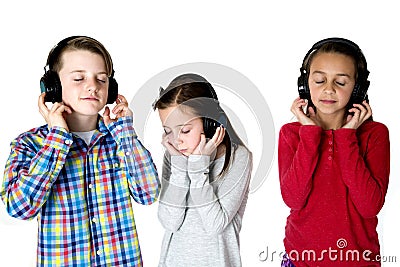 Three preteens listening to music with headphones eyes closed Stock Photo