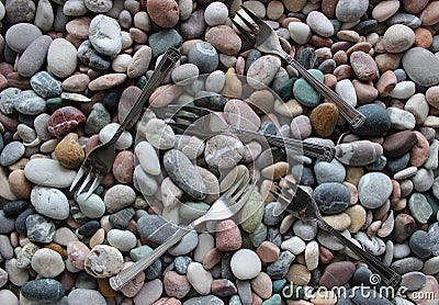 Three Pronged Forks Scattered On Smooth Sea Pebbles Stock Photo