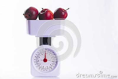 Three red apples on weighing scales Stock Photo