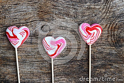 Three red lollipops in heart shape on wooden background Stock Photo