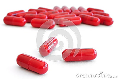 Three Red Pills (Capsules) with Many in Background Stock Photo