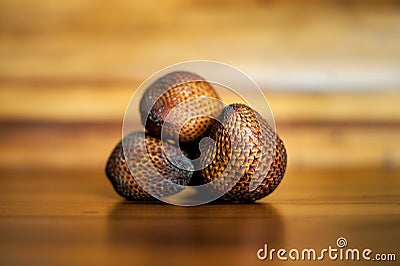 Three ripe whole salak or shake fruits lying on wooden background. Exotic fruits from Bali, Indonesia Stock Photo