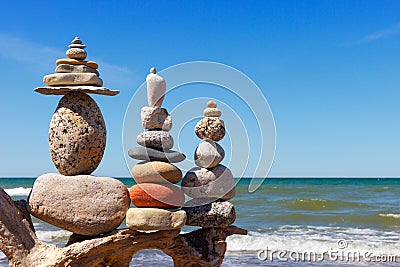 Three Rock Zen pyramid of balanced stones on a background of the summer sea and blue sky Stock Photo