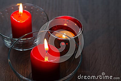 Three romantic candles on a wooden background. Home decor items. The light of the fire of paraffin candles Stock Photo