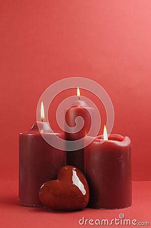 Three romantic red lit candles, vertical with copy space. Stock Photo