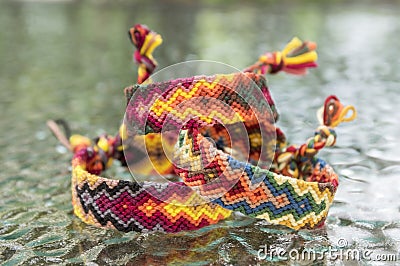 Three simple handmade homemade natural woven bracelets of friendship on glass table, rainbow colors, pattern Stock Photo