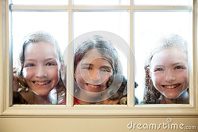 Three sister friends looking through the rainy window Stock Photo