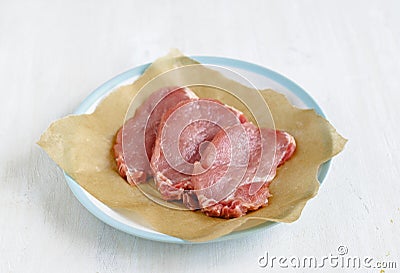 Three slices of raw meat on cooking paper Stock Photo