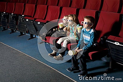 Three small children in 3D glasses watching a movie Stock Photo