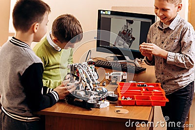 Three smart boys are making robots from the robotic constructor in the School of Robotics Stock Photo