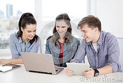 Three smiling students with laptop and tablet pc Stock Photo
