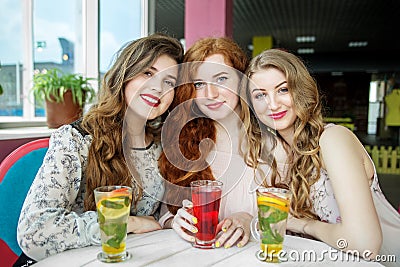 Three smiling women are sitting in a cafe. Friendship, meeting and lifestyle concept Stock Photo