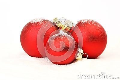 Three snowy red christmas matt balls standing on snow on white background Stock Photo