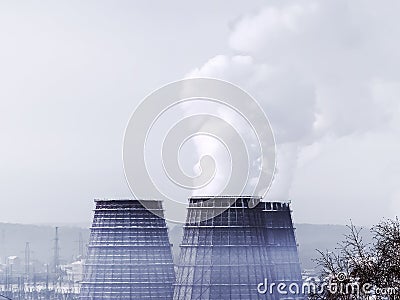 Three soaring evaporators of CHP against the blue sky. White cloud of industrial smoke or couple rises into a clean sky Stock Photo